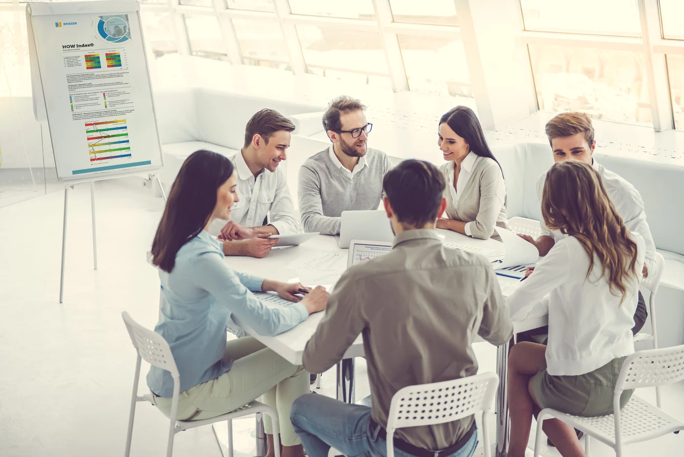 Teamsessie rond een tafel met een DISC-overzicht op de flip-over